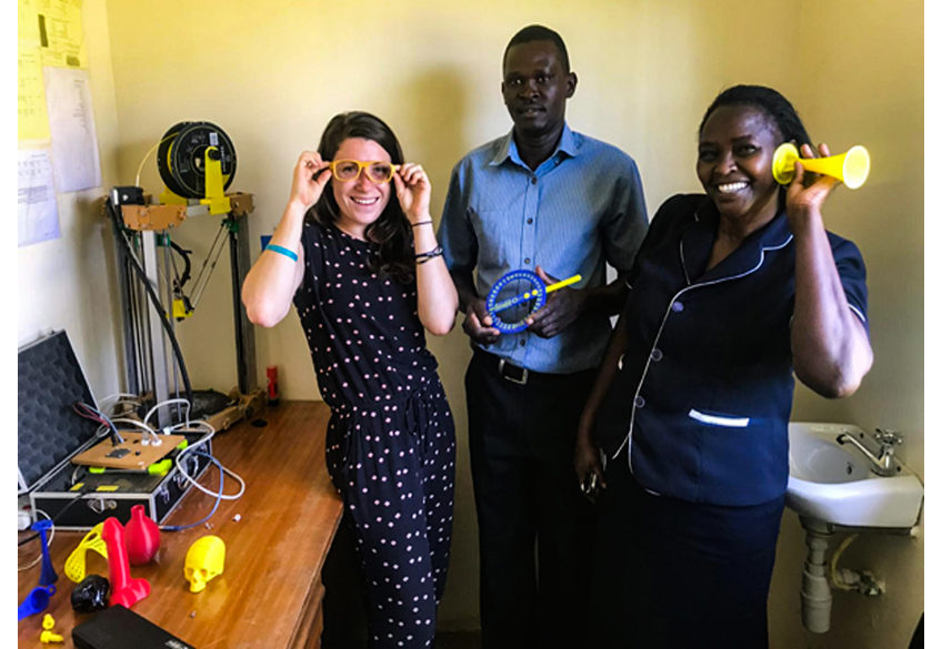 Kijenzi engineer Alenna Beroza, right, shows off 3D printed parts designed with and for nurse/administrator Jennifer Simani and biomedical engineer Daniel Obego. Beroza has spent the last four months working in Kombewa District Hospital, co-developing and testing parts with local professionals and Kijenzi engineers in the United States. Photo via Kijenzi.